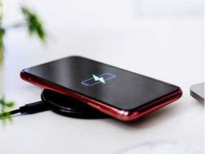 ワイヤレス充電器の上で充電中のスマホ